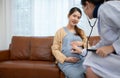 Asian pregnant woman visit gynecologist doctor at medical clinic for pregnancy consultant. Doctor examine pregnant belly for baby