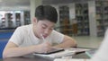 Asian preteens boys using tablet computer at library .