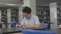 Asian preteens boys using tablet computer at library .