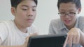 Asian preteens boys using tablet computer at library .