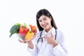 Asian pretty woman doctor, nutritionist holding and showing many fresh vegetables