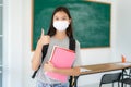 Asian primary students girl thumb up and  wearing masks to prevent the outbreak of Covid 19 in classroom while back to school Royalty Free Stock Photo