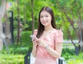 Asian professional  business woman with long hair is smiling in the garden while looking at the camera holding a smartphone in her Royalty Free Stock Photo