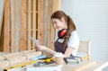 Asian professional cheerful female carpenter worker staff in apron with earphones sitting smiling showing colorful color chart