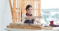 Asian professional cheerful happy female carpenter worker staff in apron with earphones canceling loud noise sitting smiling