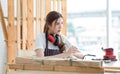 Asian professional cheerful happy female carpenter worker staff in apron with earphones canceling loud noise sitting smiling