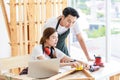 Asian professional female carpenter worker staff in apron with earphones using measuring tape measure wooden stick on workbench