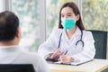 Asian professional  female doctor wears medical coat and face mask while examines and talks with a man patient in hospital Royalty Free Stock Photo