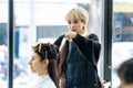 Asian professional female stylist cutting woman`s hair in salon. The woman hairdresser using scissors cut the young girl sitting i Royalty Free Stock Photo