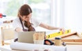 Asian professional focused female carpenter worker staff in apron sitting holding using measuring tape measure wooden sticks on Royalty Free Stock Photo