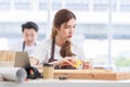 Asian professional focused female carpenter worker staff in apron sitting holding using measuring tape measure wooden sticks on Royalty Free Stock Photo