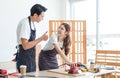 Asian professional male carpenter in apron complimenting showing thumb up to female lover worker using polishing machine rubbing