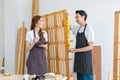 Asian professional male carpenter in apron holding using water level gauge measuring wood stick plank while female colleague