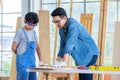 Asian professional male carpenter woodworker engineer dad in jeans outfit with safety gloves goggles helping teaching young boy Royalty Free Stock Photo