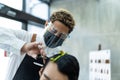 Asian professional male hairstylist combing and use scissors cutting young man customer`s hair in salon. Hairdresser wearing Royalty Free Stock Photo
