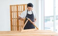 Asian professional skilled male handyman carpenter in apron using rubber hammer pounding on square triangle wood sticks and planks