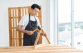 Asian professional skilled male handyman carpenter in apron using rubber hammer pounding on square triangle wood sticks and planks Royalty Free Stock Photo