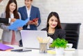 Asian professional successful businesswoman employee sitting working with laptop notebook computer on workstation desk while male Royalty Free Stock Photo