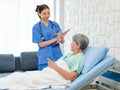 Asian professional successful female internship nurse in blue uniform with stethoscope visiting old senior elderly pensioner woman Royalty Free Stock Photo