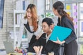 Asian professional successful male businessman in formal suit sitting working using laptop computer while two female businesswomen Royalty Free Stock Photo