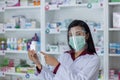 Asian Professional women pharmacist with protective face shield on his face working in modern drugstore and showing white medicine Royalty Free Stock Photo