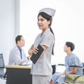 Asian professional young cheerful female nurse in white uniform standing smiling crossed arms holding document clipboard while Royalty Free Stock Photo