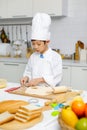 Asian professional young little boy pastry chef in white cooking uniform and tall cook hat standing using heart shape mold cutting Royalty Free Stock Photo