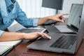 Asian programmer woman pointing and looking on multiple laptop screen to writing code and database