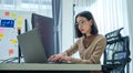 Asian prompt engineer develop coding app with software data sitting in front of computer monitor at office