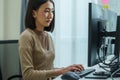Asian prompt engineer develop coding app with software data sitting in front of computer monitor at office
