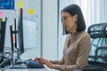 Asian prompt engineer developer coding app with software data sitting in front of computer monitor at office