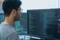 Asian prompt engineer developer coding app with software data sitting in front of computer monitor at office