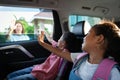 Asian pupil girl with backpack and her sister sitting in the car and waving goodbye to her mother Royalty Free Stock Photo