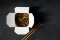 Asian restaurant food delivery. Soba noodles with meat, vegetables and soy sauce in white take-out paper box on black background Royalty Free Stock Photo
