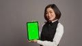 Asian restaurant hostess showing greenscreen display in studio