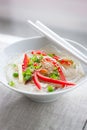 Asian rice noodles with vegetables and sesame in a bowl on a linen textile background