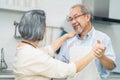 Asian romance senior elderly couple stay at home enjoy cook in kitchen. Happy Grandfather hug grandmother dance together, enjoy Royalty Free Stock Photo