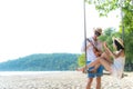 Asian romantic couple is sitting on sea beach on rope swing relax and happiness for holiday. Honeymoon relax together on summer t