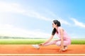 Asian runner woman stretching legs before starting the run on the running track Royalty Free Stock Photo