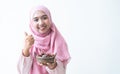 Asian 30s Muslim woman wearing traditional clothes with pink hijab headscarf, smiling holding a bowl of dry dates fruit in hands, Royalty Free Stock Photo