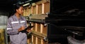 Asian 20s woman in grey uniform check count items in warehouse storage room. Maintenance Service