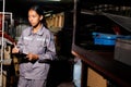 Asian 20s woman in grey uniform check count items in warehouse storage room. Maintenance Service