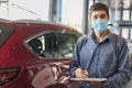 Asian saleman wear surgical mask working in inspector checking writing on clipboard in garage of dealership Wait mechanic In