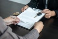 Asian salesman holding rental contract and hand over car key to client while he is holding pen to signing Royalty Free Stock Photo