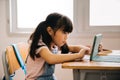 Asian school girl using digital device in school classroom, digital native, technology, learning, touchscreen. Female
