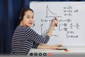 Asian school woman teacher working from home teach online math to student studying from home. Teacher writeing on whiteboard and