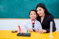 Schoolgirl and beautiful teacher sitting in classroom