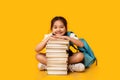 Asian Schoolgirl Sitting At Book Stack On Yellow Studio Background Royalty Free Stock Photo