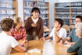 Asian schoolgirl talking in front of team of schoolkids during classes in library Royalty Free Stock Photo