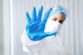 Asian Scientific experimenter Woman Wearing blue protective rubber gloves and showing stop hand sign for Covid-19 virus pathogens